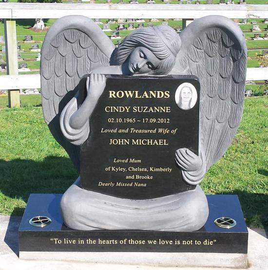Custom headstone with an angel cuddling a square plaque crafted from granite by Stoneworx - Memorials of Distinction in New Zealand.