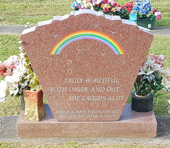 Custom shape headstone in red granite with a rainbow and bird designs crafted from granite by Stoneworx - Memorials of Distinction in New Zealand.